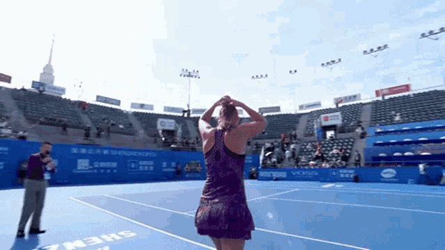 a woman in a purple dress stands on a blue tennis court