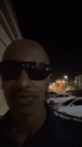 a man wearing sunglasses and a blue shirt is smiling