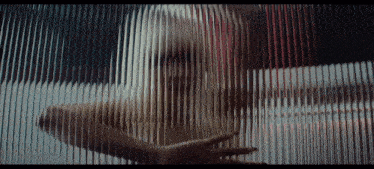 a woman is behind a glass wall with a striped pattern