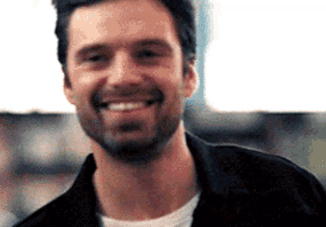 a close up of a man with a beard smiling for the camera .