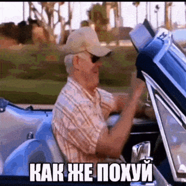 a man in a hat is driving a car with a caption that says как же похуй