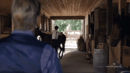 a man standing next to a horse in a stable that says hallmark on the bottom