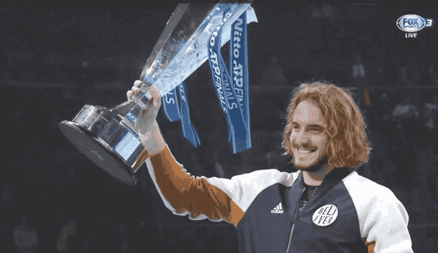 a man holding a trophy with a fox logo in the background