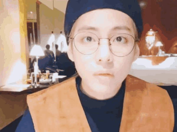 a man wearing glasses and a hat is making a face