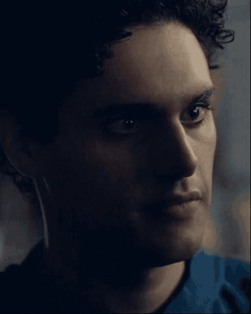 a man with curly hair is wearing a blue shirt