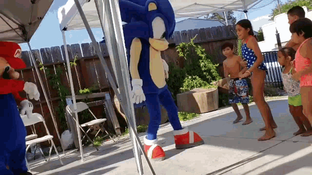 a sonic the hedgehog mascot is standing next to a mario mascot