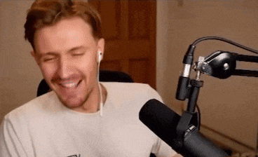 a man is sitting in front of a microphone with his eyes closed and smiling .