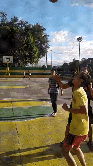 a group of people are playing basketball on a court with a basketball hoop in the background