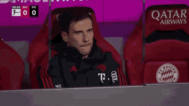 a soccer player sits in the dugout with a qatar airways seat