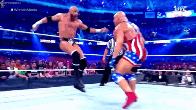 a wrestler in an american flag outfit is jumping over another wrestler in a ring