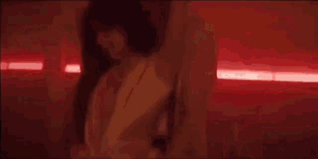 a woman in a white dress is dancing in a dark room with red lights .