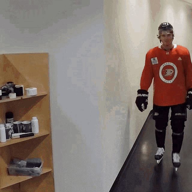 a hockey player is walking down a hallway wearing a red jersey that says ' arizona coyotes ' on it