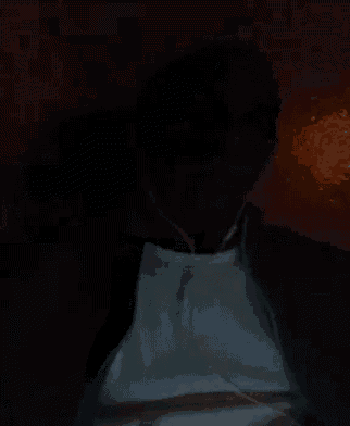 a man is standing in the dark wearing headphones and a white apron .