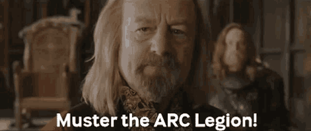 a man with long blonde hair and a beard is standing in a room and says `` muster the arc legion ! ''
