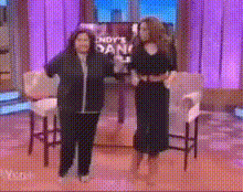 two women are dancing on a stage in front of a sign that says ' andy 's dan '