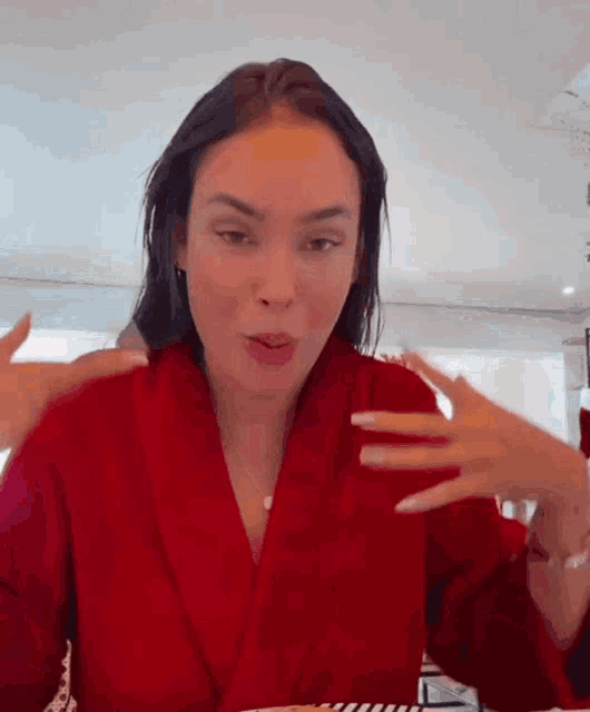 a woman in a red robe is making a face