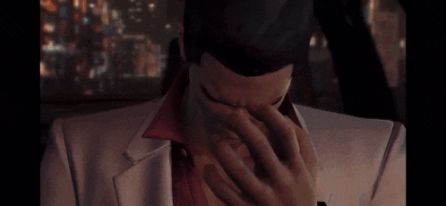 a man in a suit is covering his face with his hand .