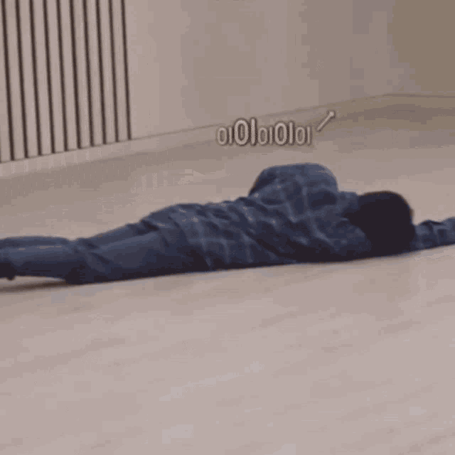 a man in a plaid shirt is laying on a wooden floor