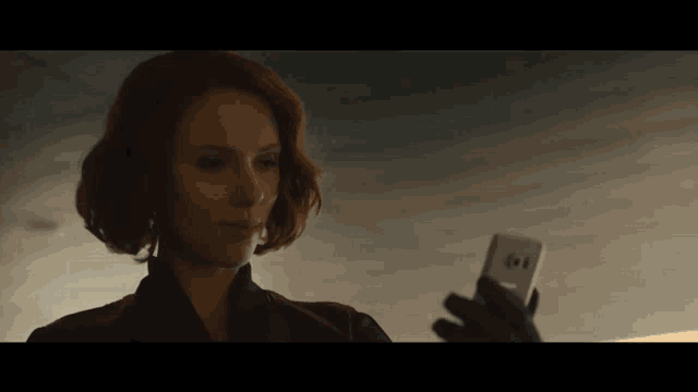 a woman with red hair is holding a cell phone in her hand