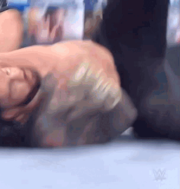 a man is laying on the ground in a wrestling match with a wrestling logo in the background .