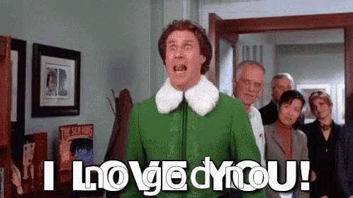 a man in a green jacket is standing in front of a group of people and saying i love you .