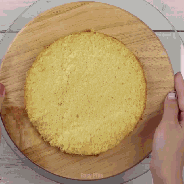 a person is frosting a cake with a piping bag on a wooden table .