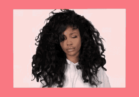 a woman with curly hair is wearing a white hoodie and making a funny face .