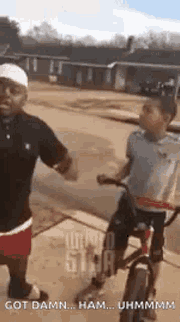 a man and a boy are riding a bike down a street .