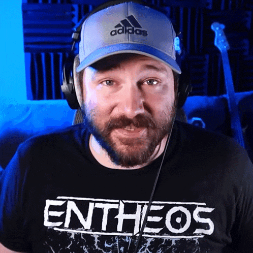 a man wearing a hat and headphones is wearing an entheos t-shirt