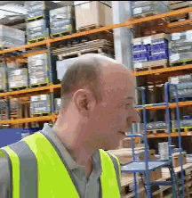a man wearing a yellow vest stands in front of a warehouse