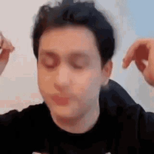 a man is making a funny face with his eyes closed and his hands on his head .