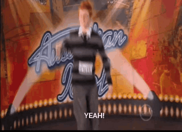 a man is dancing in front of an american idol poster