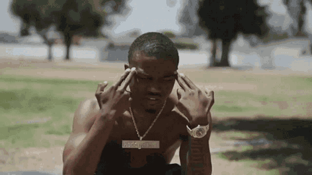 a shirtless man wearing a watch and a necklace with a pendant that says roddy ricch