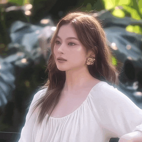 a woman wearing a white shirt and gold earrings