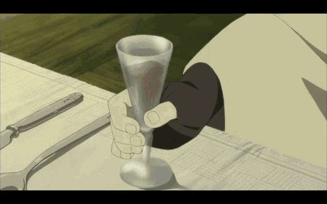 a person is holding a glass with a red liquid inside of it