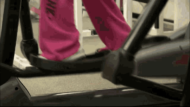 a person in pink pants is walking on an elliptical