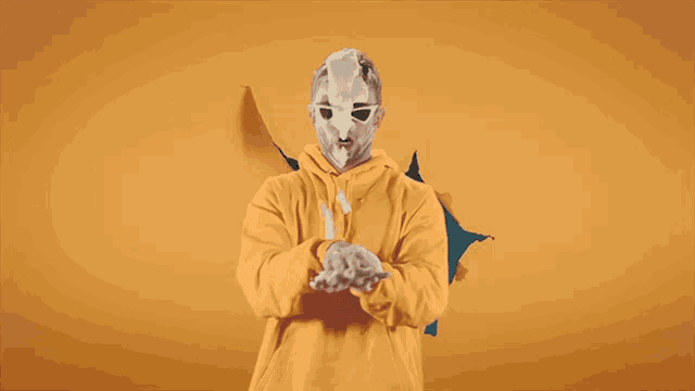 a man wearing a yellow hoodie and a white mask