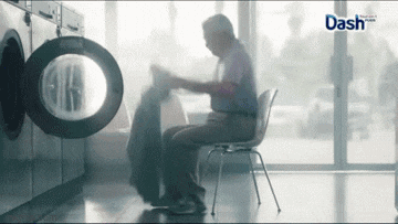 a man is sitting in a chair in front of a washing machine with the word dash on the bottom