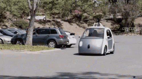 a small silver car is driving down a road with other cars