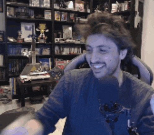 a man is sitting in front of a microphone and smiling while playing a video game .