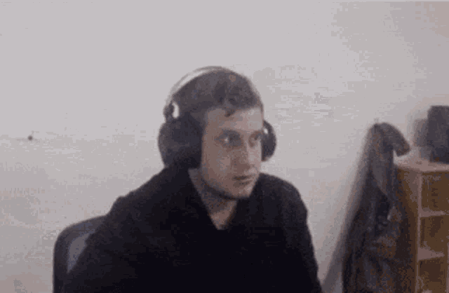 a man wearing headphones is sitting in a chair in front of a computer screen .