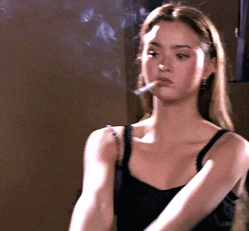 a woman is smoking a cigarette in a dark room
