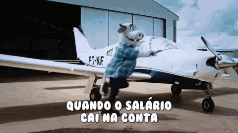 a pig mascot is standing next to a small plane with the letters pt-nif on the tail