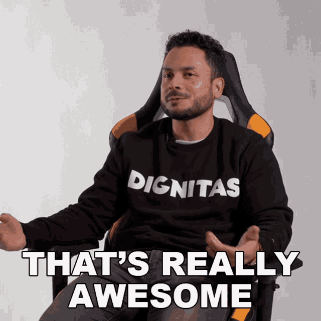 a man wearing a black dignitas sweatshirt is sitting in an office chair
