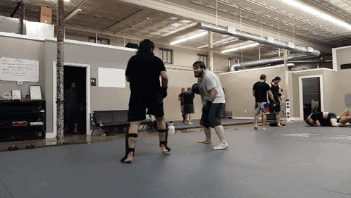 a group of men are practicing martial arts in a gym with a sign on the wall that says ' no smoking '