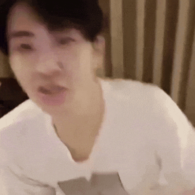 a man in a white t-shirt is making a funny face in a blurry photo .