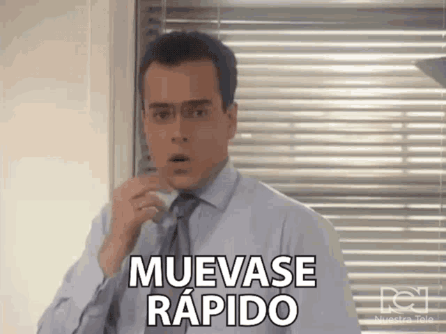 a man in a suit and tie is talking on a cell phone and says muevase rapido .