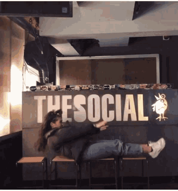 a woman is doing a flip in front of a sign that says thesocial
