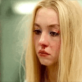 a close up of a woman with a bloody nose and a broken eye .