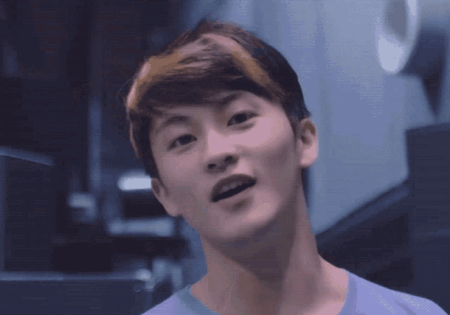a close up of a young man 's face with a purple shirt